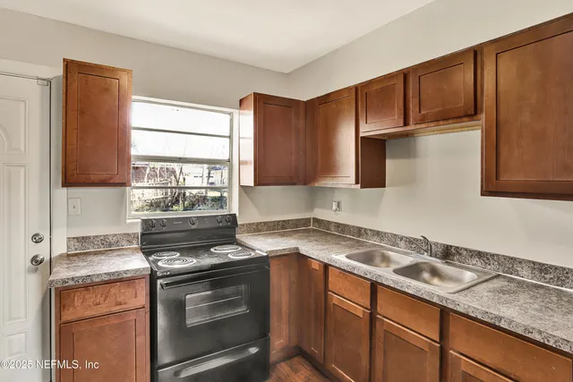 a kitchen with granite countertop a sink cabinets stainless steel appliances and a window