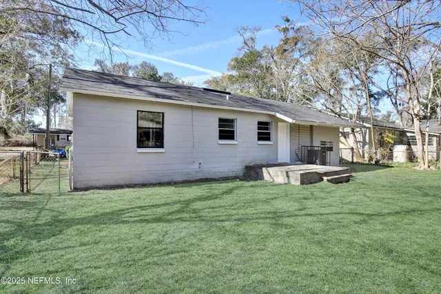 a view of a backyard with plants and large tree
