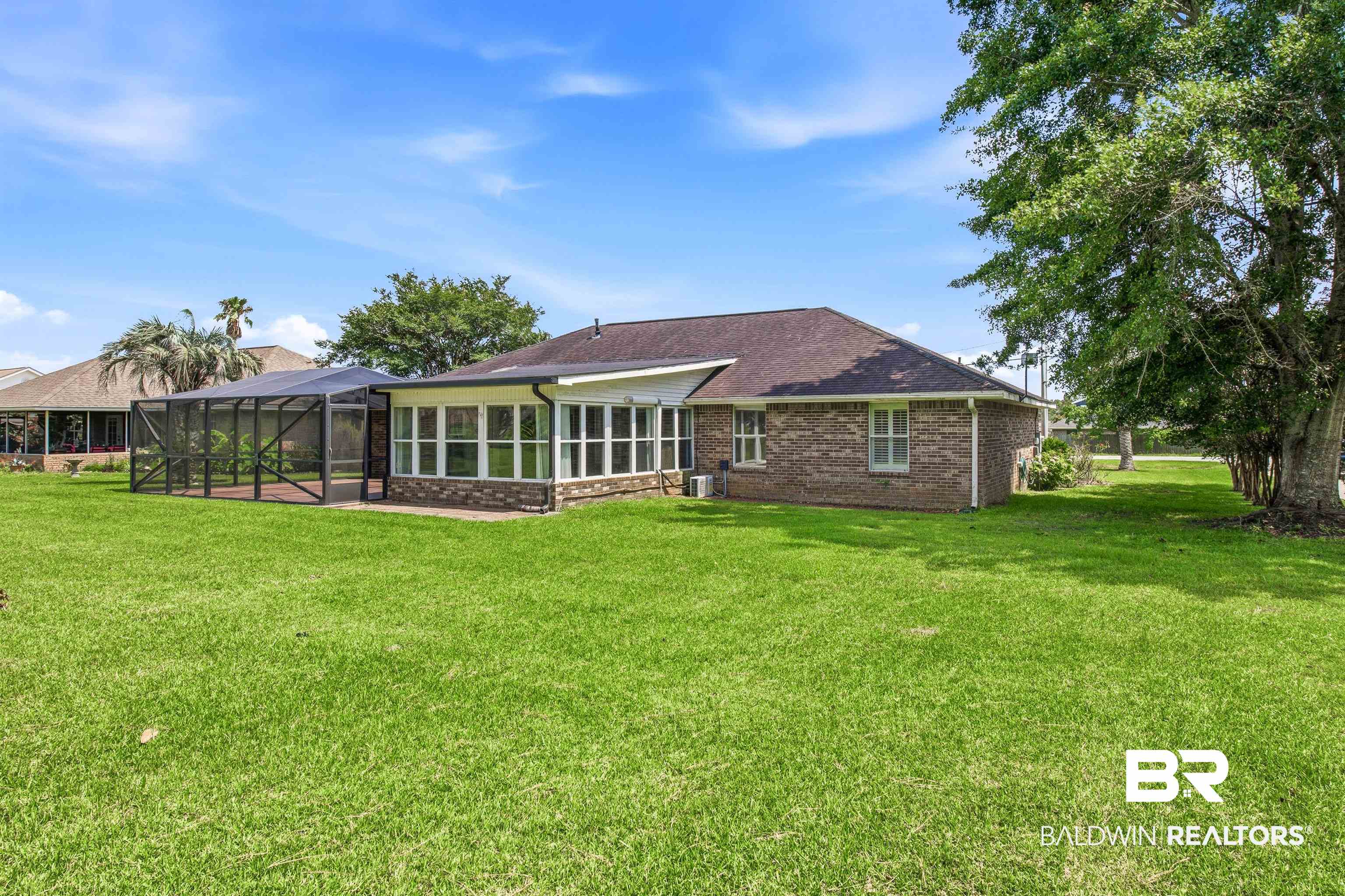 22685 County Road 12 Foley, AL 36535 - Photo 12 of 89 Expansive green lawn bordering a brick exterior residence featuring a screened enclosure and a sunroom with large windows