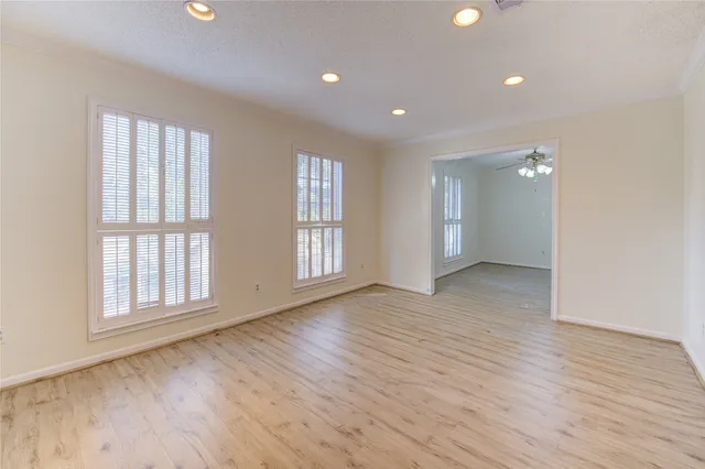 an empty room with wooden floor and windows
