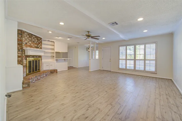 an empty room with wooden floor and a fireplace