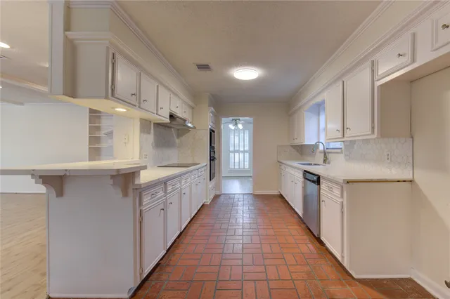 a large white kitchen with cabinets a sink a window and stainless steel appliances
