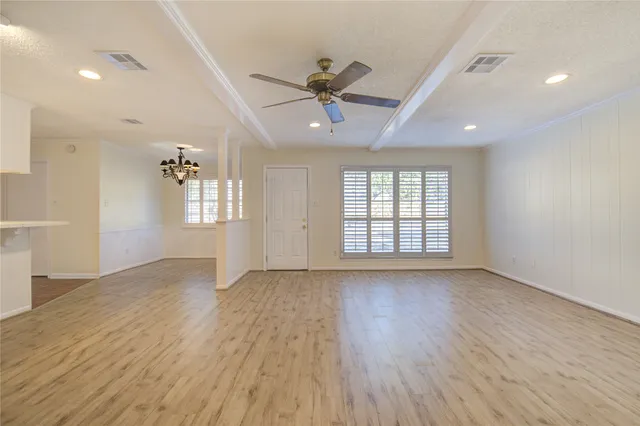 a view of an empty room with a window and wooden floor