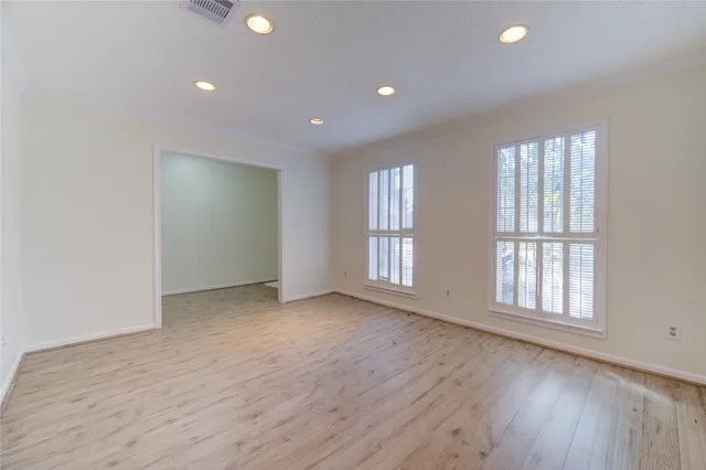 an empty room with wooden floor and windows with curtains view