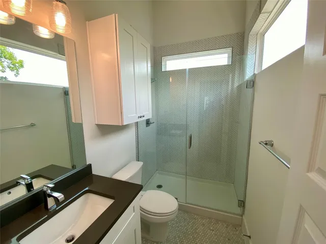 a bathroom with a granite countertop sink a toilet and shower