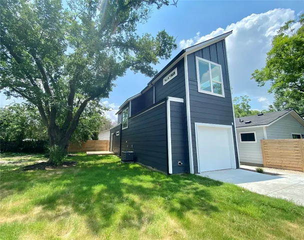 a view of backyard with large tree and wooden fence