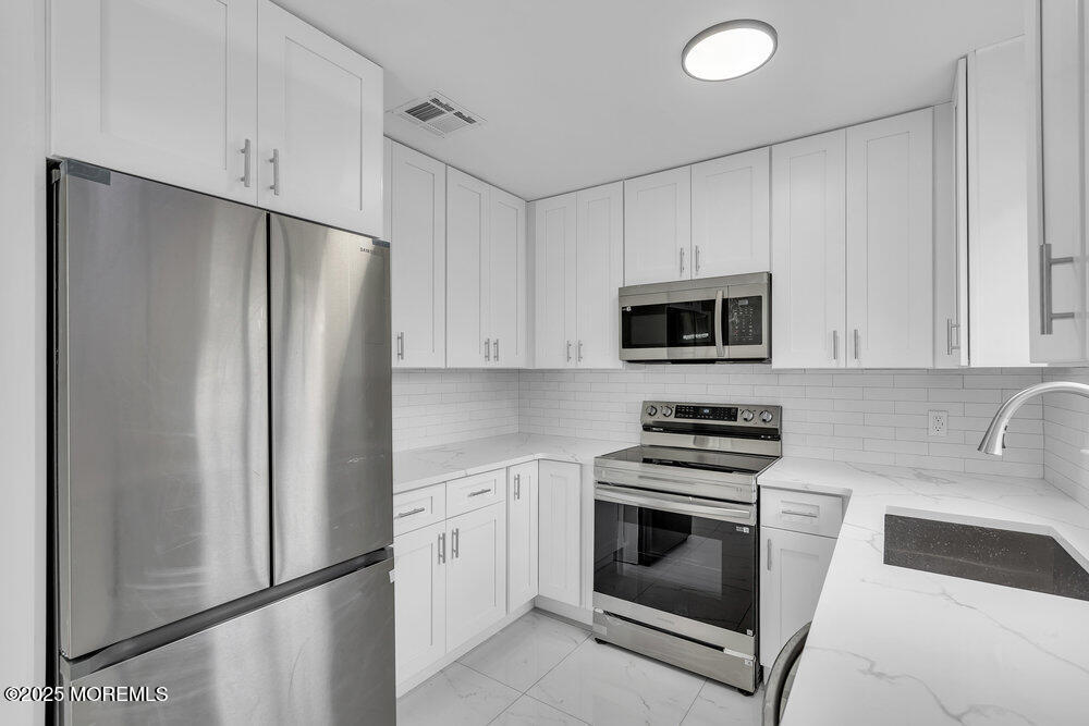9B Juniper Lane, Unit 50 Whiting, NJ 08759 - Photo 16 of 28 a kitchen with white cabinets and stainless steel appliances