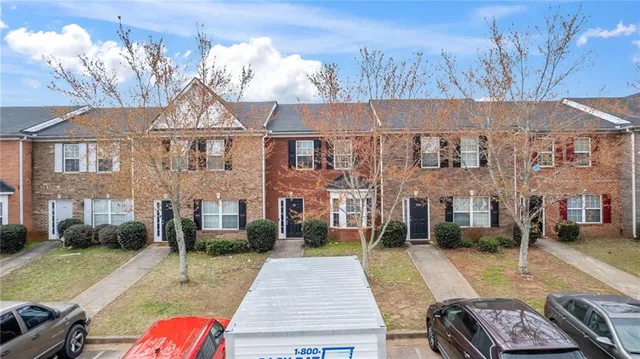 a view of a brick house with many windows next to a yard