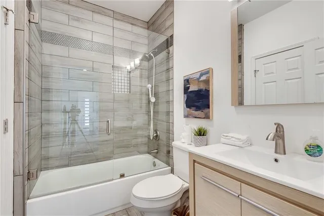 a bathroom with a bathtub shower sink mirror vanity and toilet