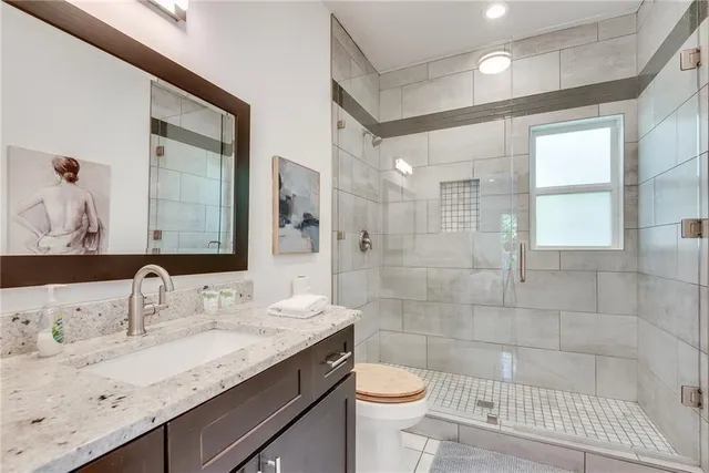 a bathroom with a granite countertop sink a toilet and shower