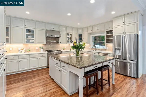 a kitchen with stainless steel appliances kitchen island granite countertop a sink stove and refrigerator