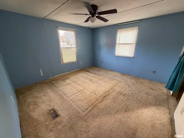 en empty room with windows and ceiling fan