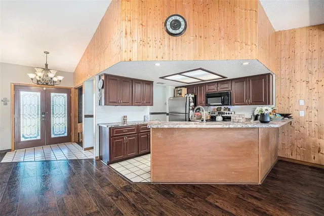 a living room with stainless steel appliances kitchen island granite countertop wooden floors and a fireplace