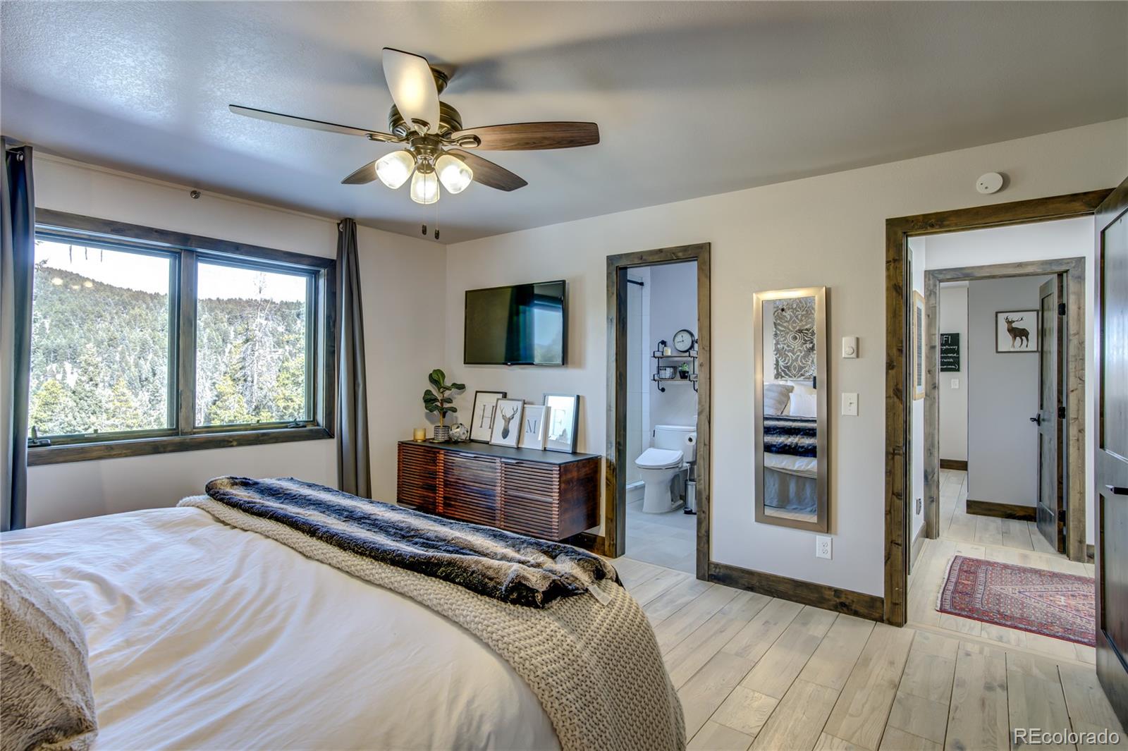 19273 Silver Ranch Road Conifer, CO 80433 - Photo 23 of 37 a bedroom with a bed and a chandelier