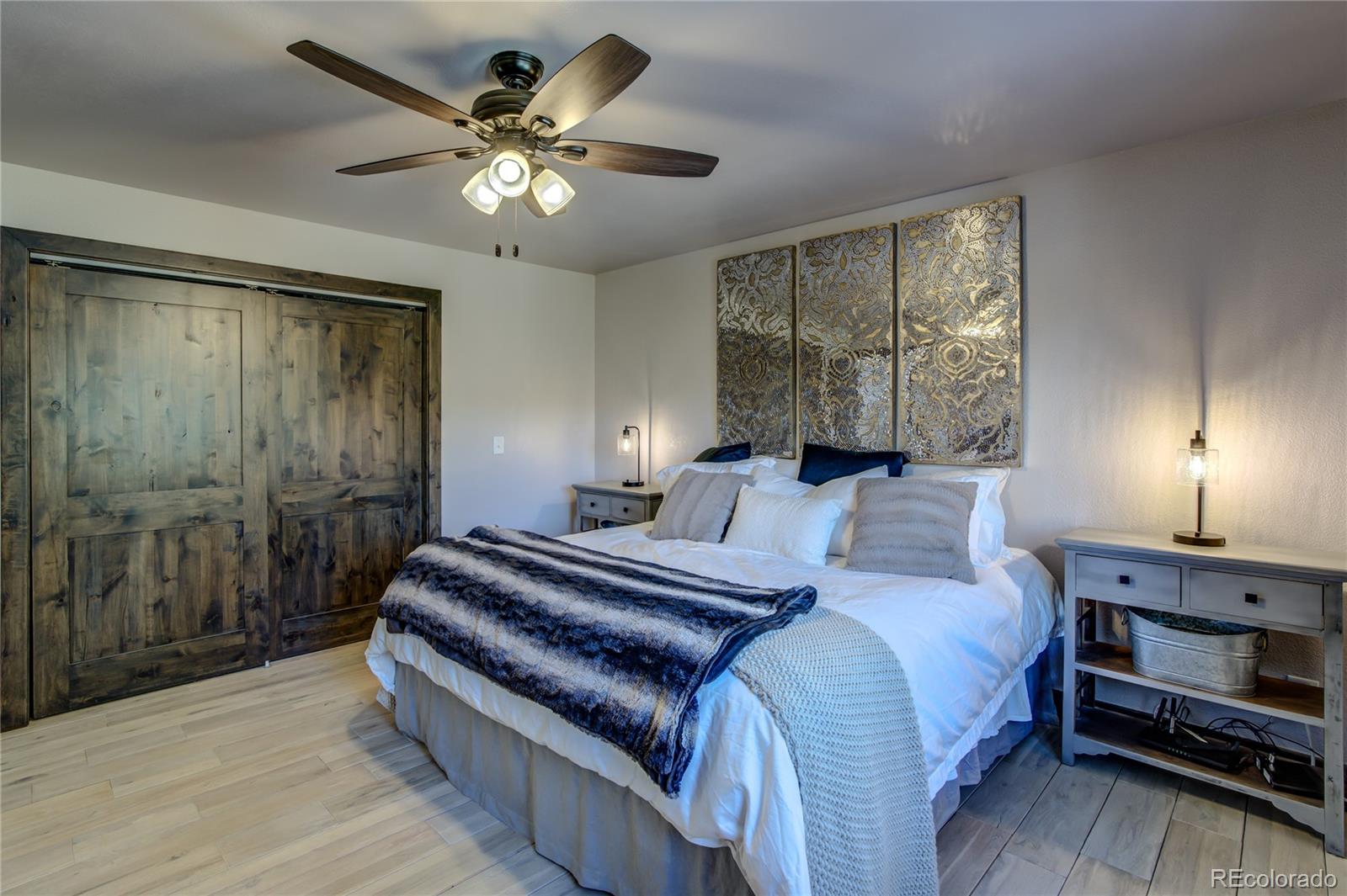 19273 Silver Ranch Road Conifer, CO 80433 - Photo 24 of 37 a spacious bedroom with a bed and a chandelier