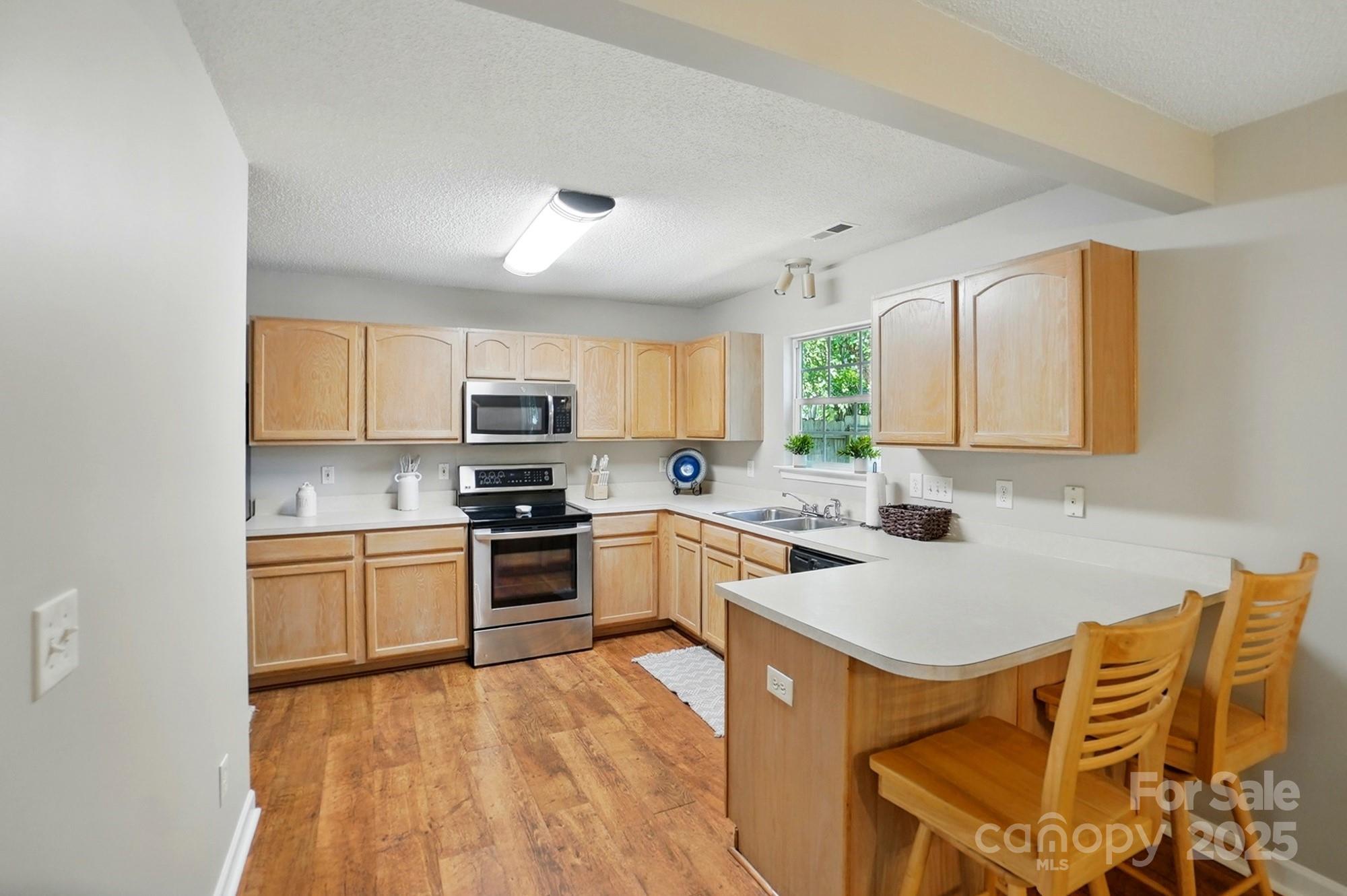 820 Settlement Street Clover, SC 29710 - Photo 8 of 29 a kitchen with stainless steel appliances granite countertop a stove top oven a sink dishwasher and white cabinets with wooden floor