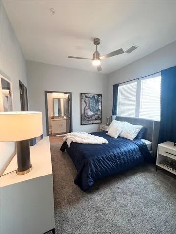 a spacious bedroom with a bed a window and dresser