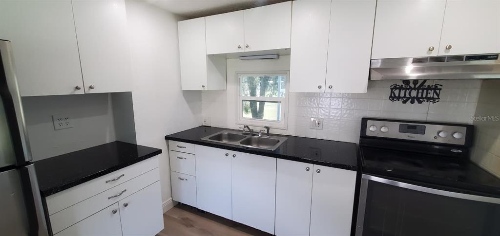 4305 Tony Street Orlando, FL 32808 - Photo 9 of 23 a kitchen with granite countertop a stove and a refrigerator