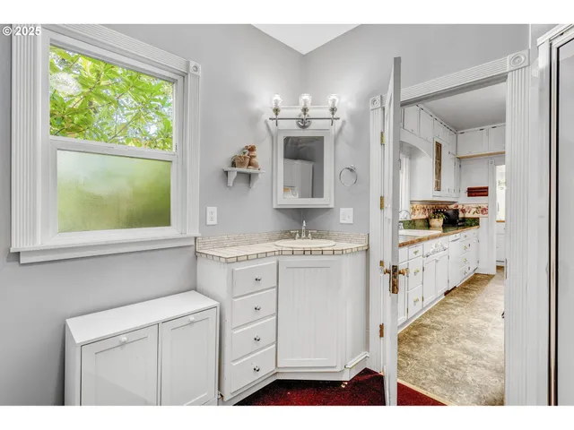 a kitchen with white cabinets and window