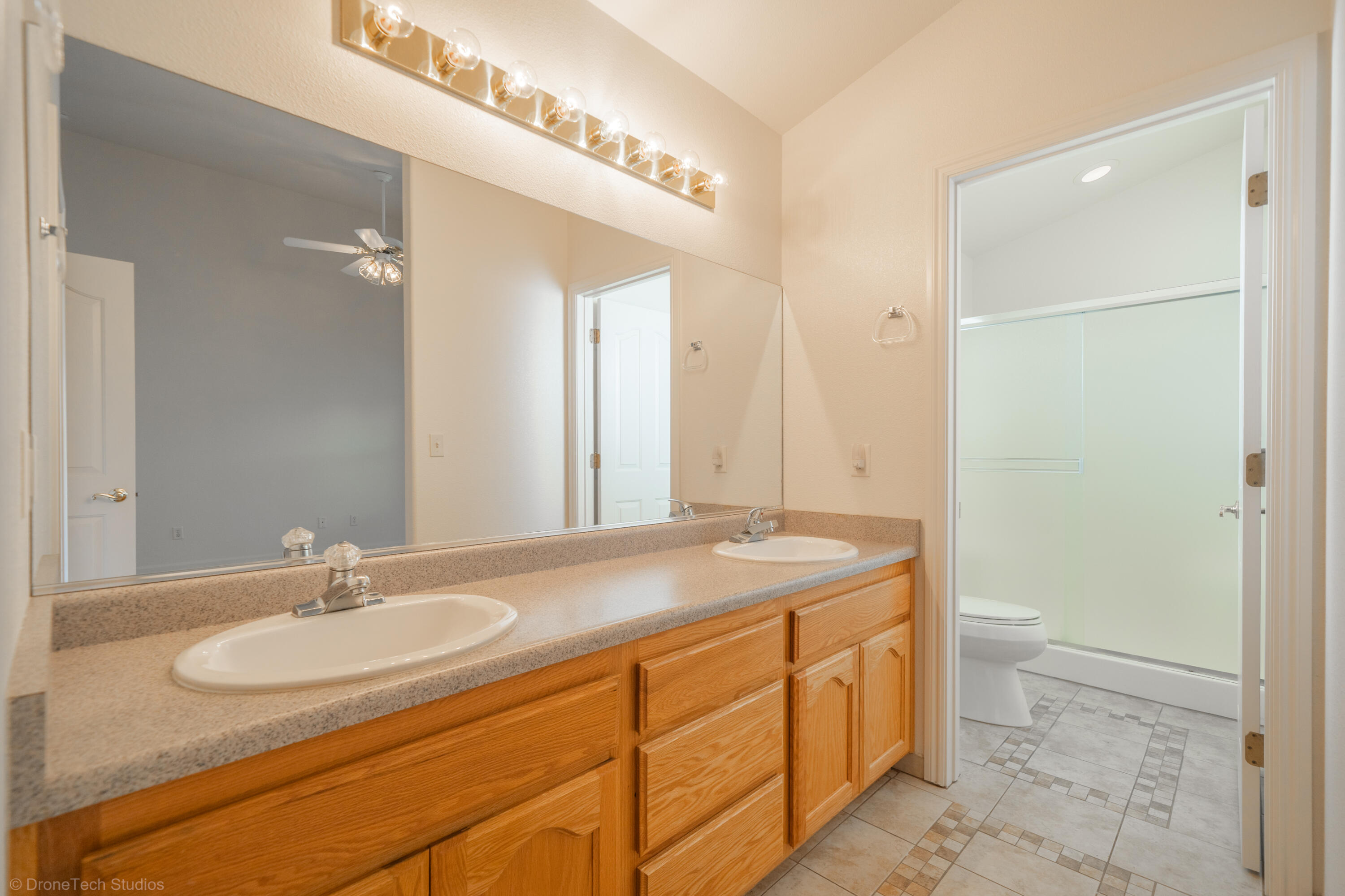 1764 Capistrano Walk Redding, CA 96003 - Photo 21 of 34 a bathroom with a granite countertop sink a toilet and a mirror