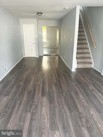 a view of an empty room with wooden floor and stairs