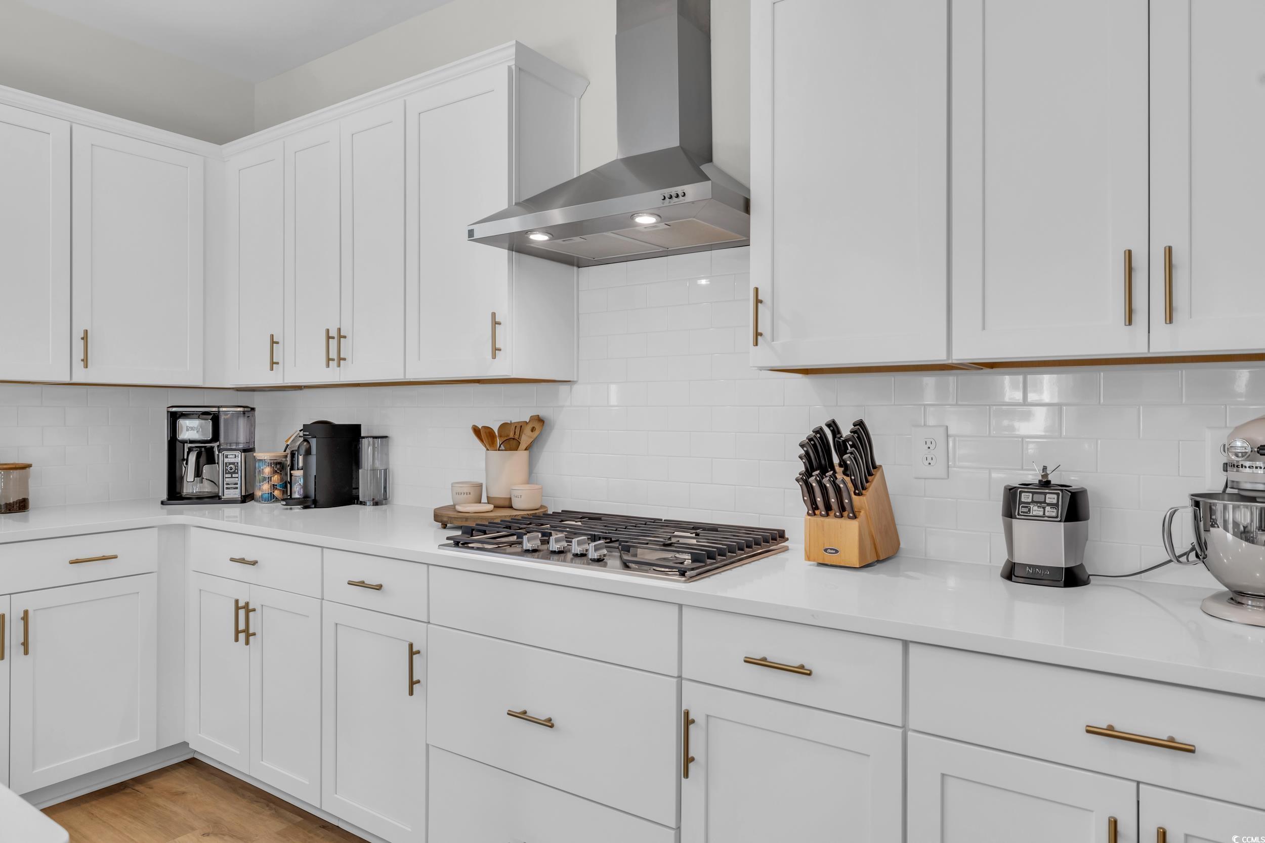 157 Tidal Drive Murrells Inlet, SC 29576 - Photo 13 of 36 Kitchen featuring white cabinetry, decorative backsplash, wall chimney exhaust hood, and stainless steel gas stovetop