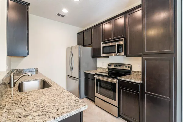a kitchen with stainless steel appliances granite countertop a refrigerator a stove a sink and dishwasher