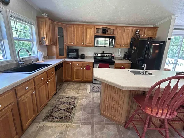 a kitchen with stainless steel appliances a sink a stove a refrigerator cabinets and a window
