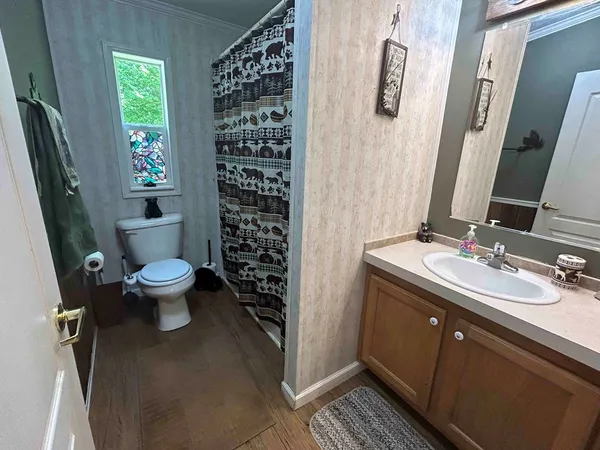 a bathroom with a granite countertop toilet a sink a shower and a mirror
