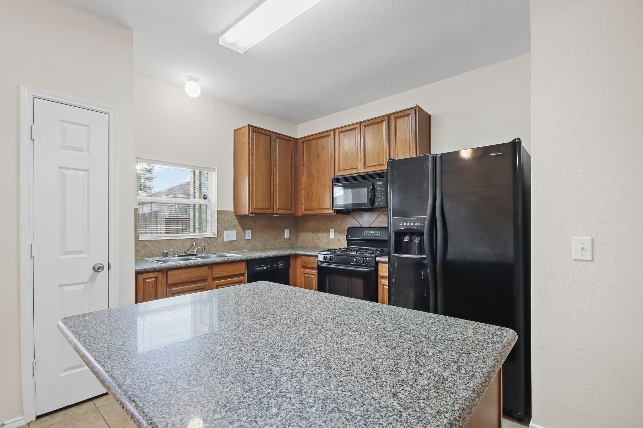 3526 Glenmore Meadow Drive Spring, TX 77386 - Photo 5 of 23 a kitchen with granite countertop a refrigerator and a stove top oven