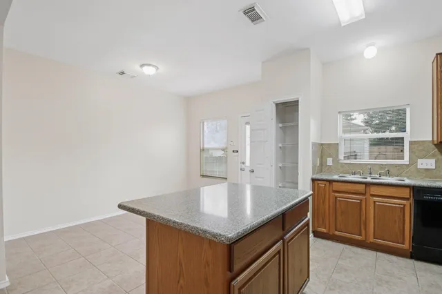 a kitchen with granite countertop a refrigerator and a stove top oven