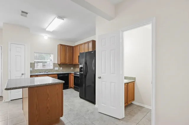 a view of a kitchen with kitchen island granite countertop wooden cabinets and stainless steel appliances