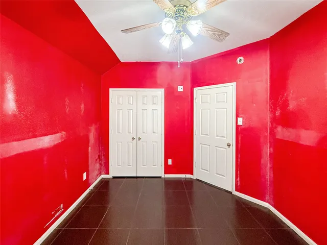 a view of an empty room with window and chandelier fan