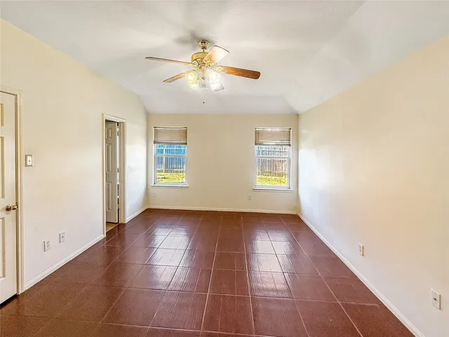 a view of an empty room with window and chandelier fan