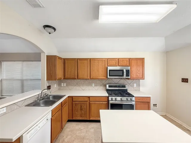 a kitchen with stainless steel appliances granite countertop a sink and a refrigerator