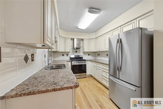 a kitchen with granite countertop stainless steel appliances a refrigerator a sink a stove and cabinets