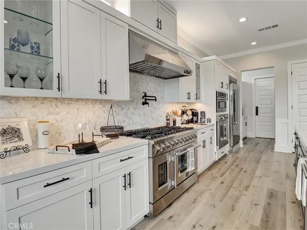 a kitchen with stainless steel appliances granite countertop a stove a sink and white cabinets