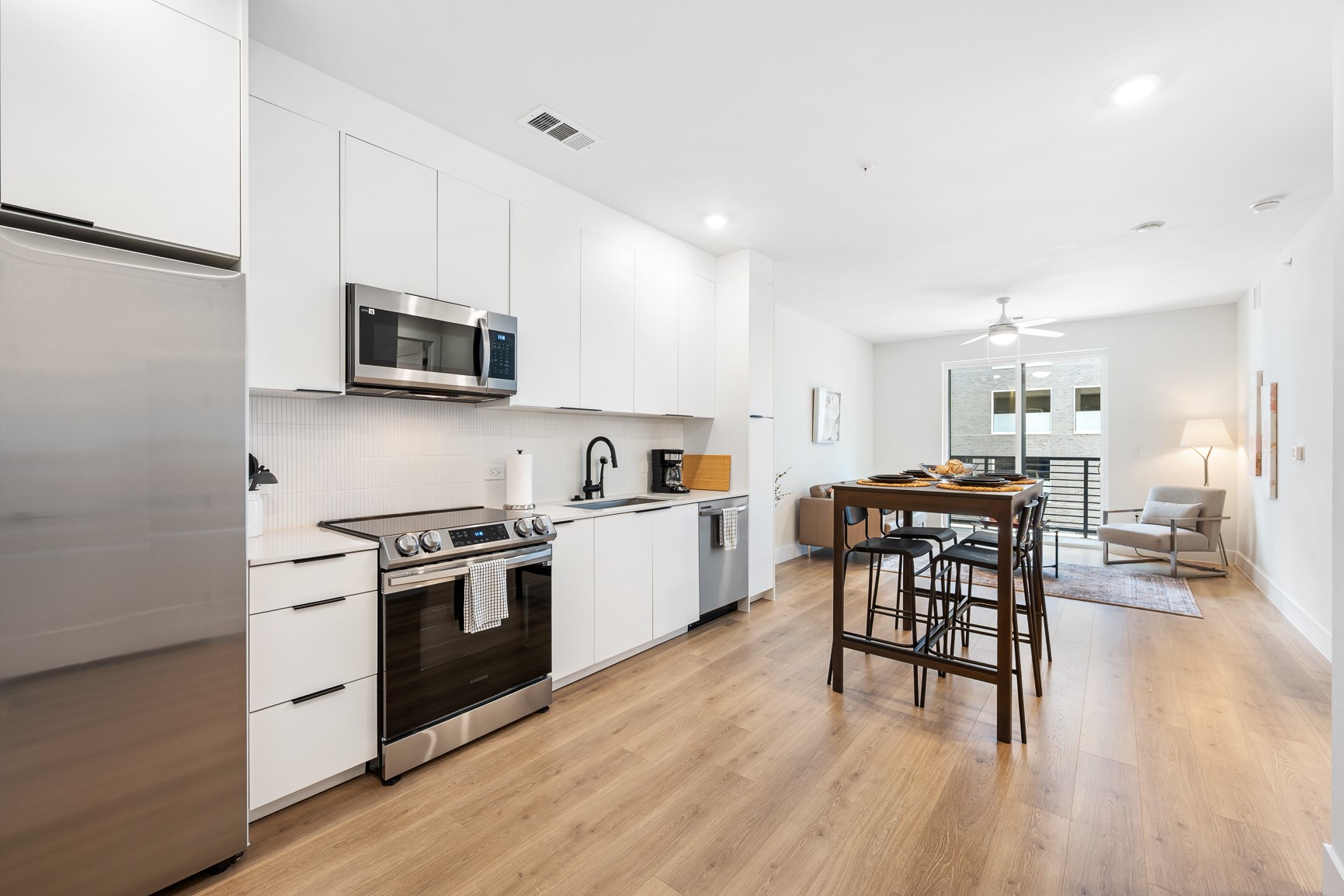 1701 Simond Avenue, Unit 201 Austin, TX 78723 - Photo 6 of 20 a kitchen with a stove top oven a sink dishwasher a dining table and chairs with wooden floor
