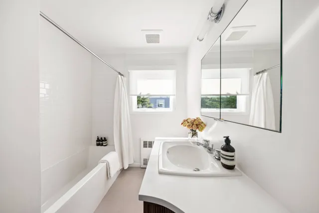 a bathroom with a sink a tub and a window