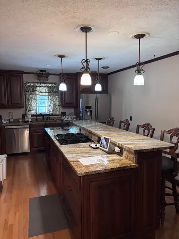 a kitchen with stainless steel appliances granite countertop a sink a stove and a wooden floors