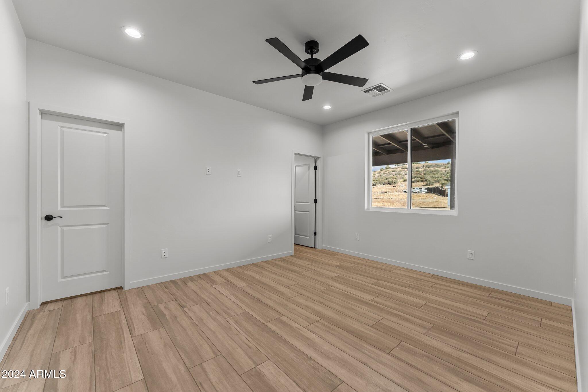 18473 Henry Coe Road Peeples Valley, AZ 86332 - Photo 17 of 31 an empty room with wooden floor and windows