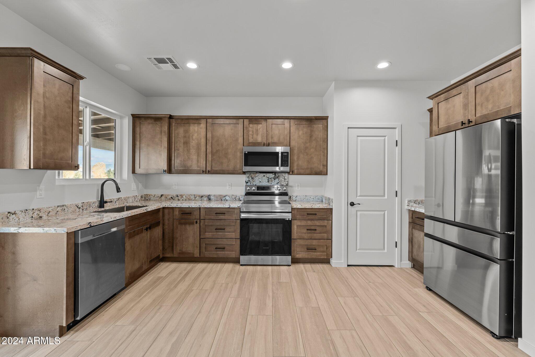 18473 Henry Coe Road Peeples Valley, AZ 86332 - Photo 2 of 31 a kitchen with granite countertop stainless steel appliances and wooden cabinets