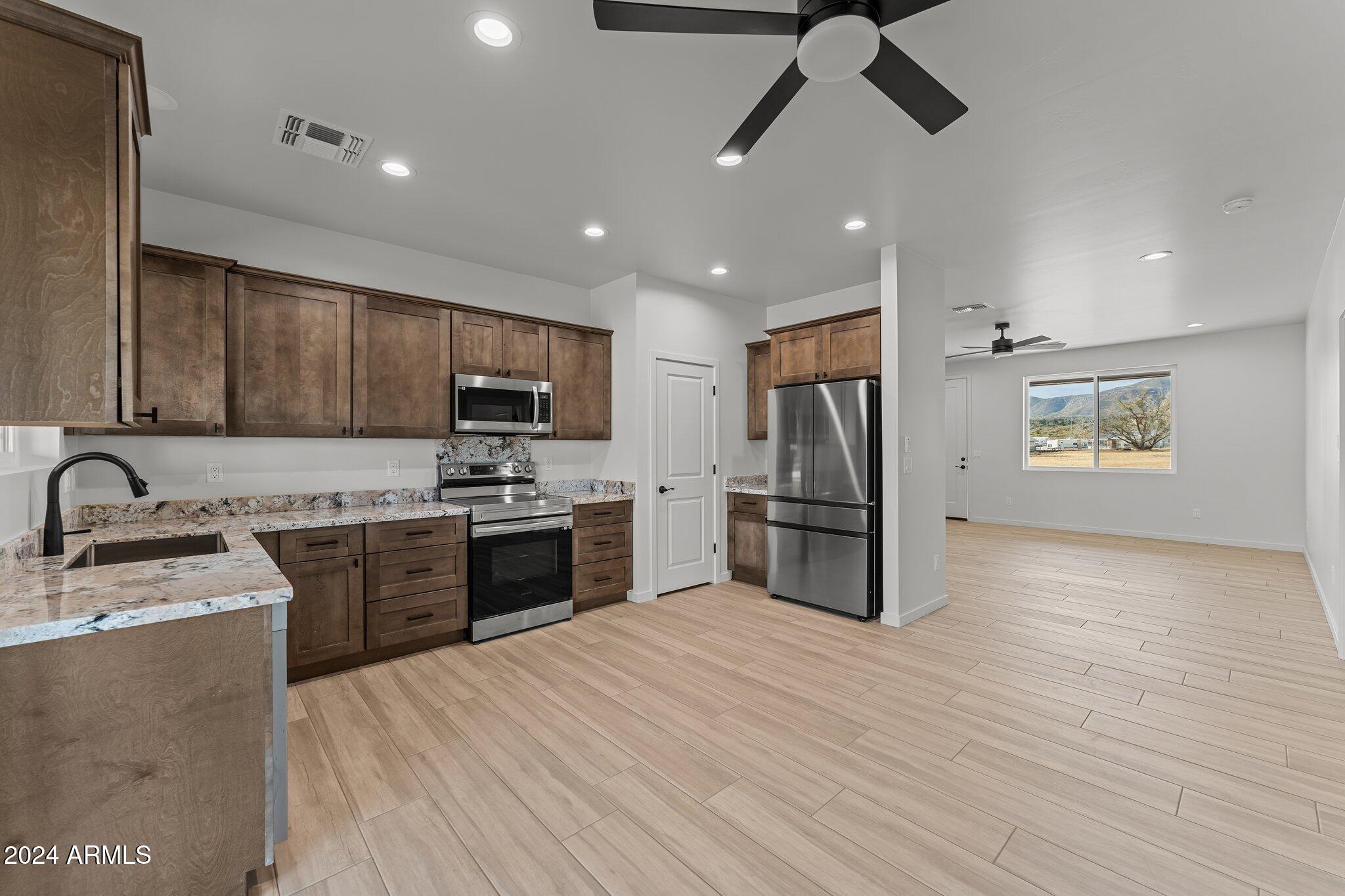 18473 Henry Coe Road Peeples Valley, AZ 86332 - Photo 7 of 31 a kitchen with stainless steel appliances granite countertop a sink refrigerator and cabinets
