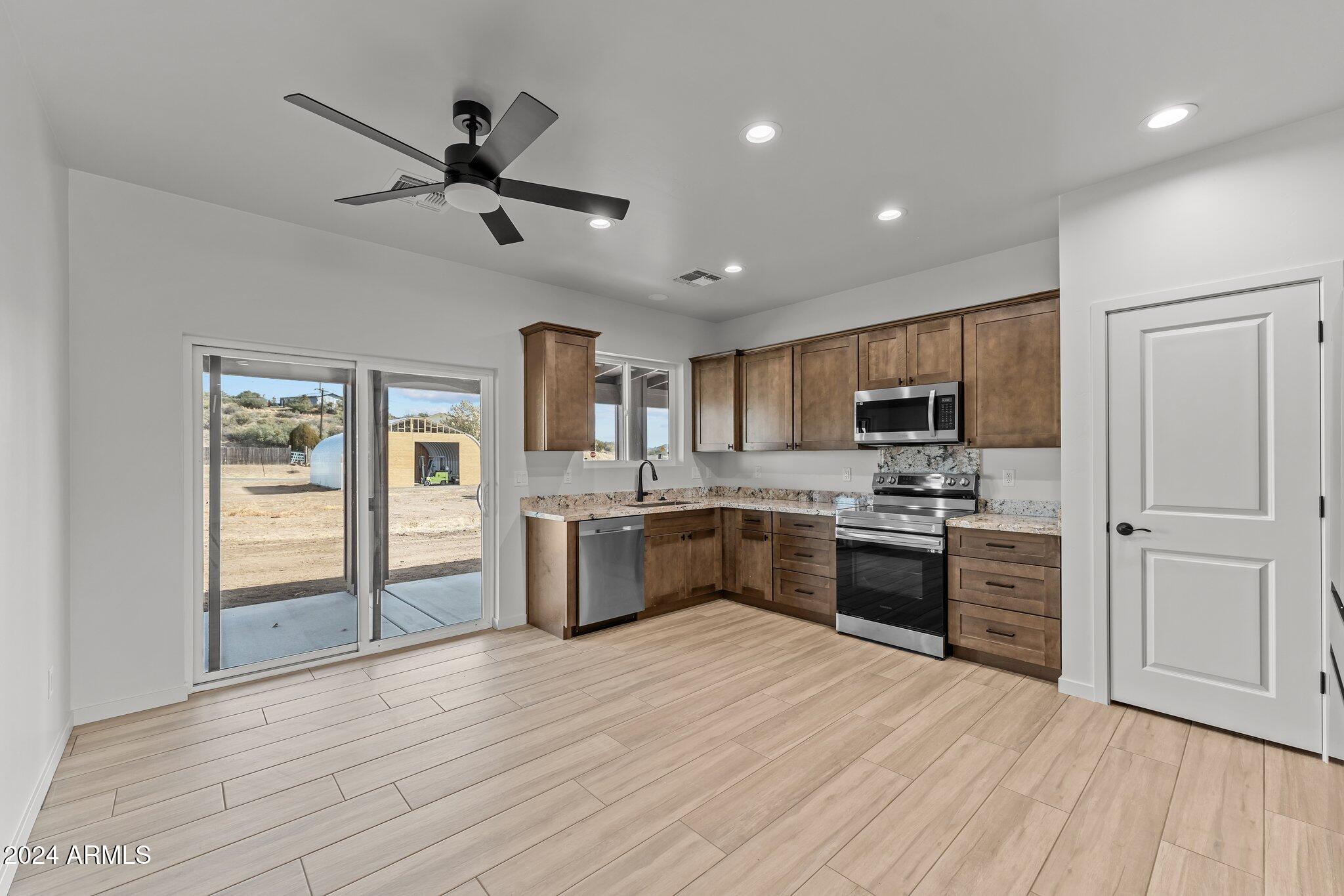 18473 Henry Coe Road Peeples Valley, AZ 86332 - Photo 9 of 31 a large kitchen with cabinets wooden floor and stainless steel appliances