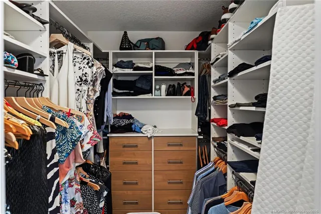 a view of walk in closet with clothes and shoes
