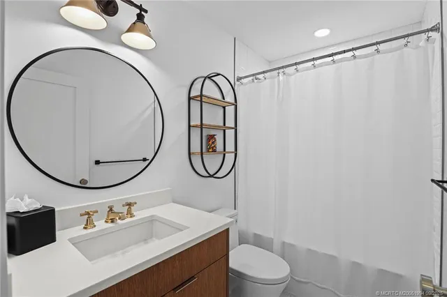 a bathroom with a sink vanity mirror and toilet