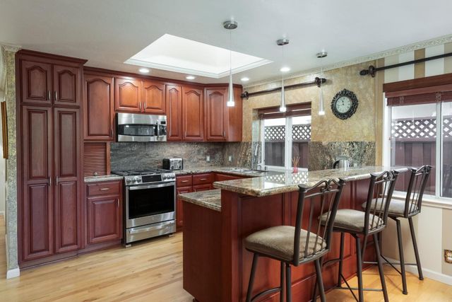 a kitchen with stainless steel appliances granite countertop wooden cabinets a stove top oven a sink and dishwasher