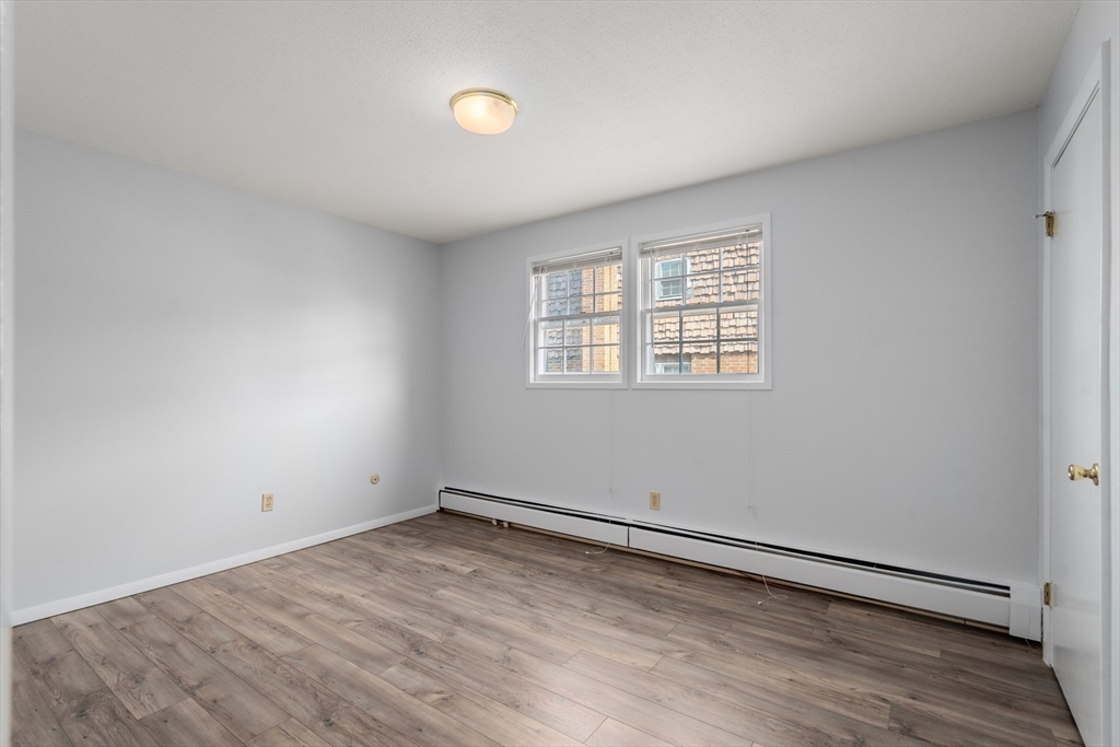 88 Beacon Street, Unit 7 Lawrence, MA 01843 - Photo 20 of 34 an empty room with wooden floor and windows
