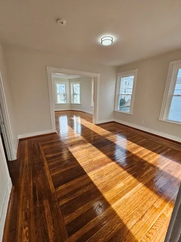 a bedroom with wooden floor and window