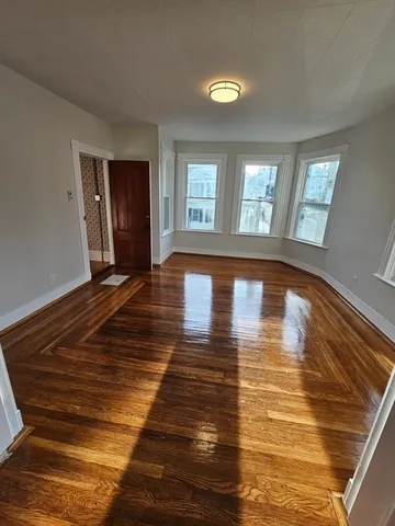 a view of empty room with window and wooden floor